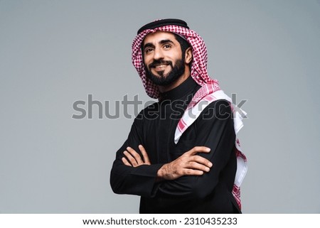Handsome arab middle-eastern saudi arabian man with traditional saudi clothing in studio - Arabic muslim adult male businessman wearing thwab portrait isolated on gray background Royalty-Free Stock Photo #2310435233