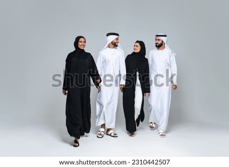 Beautiful arab middle-eastern women with traditional abaya dress and middle easter man wearing kandora in studio - Group of arabic muslim adults portrait in Dubai, United Arab Emirates Royalty-Free Stock Photo #2310442507
