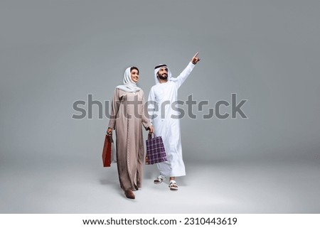 Beautiful arab middle-eastern happy couple of lovers wearing traditional abaya and kandora in studio - Arabic muslim adult people bonding and having fun in Dubai, United Arab Emirates Royalty-Free Stock Photo #2310443619
