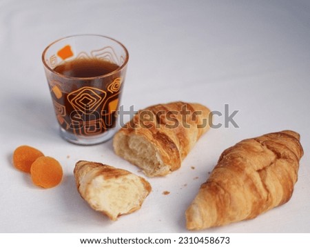 Croissants, dried apricots and black coffee in a glass on a white background look delicious, minimalistic, stylish and refreshing.