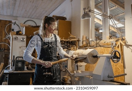 Craftswoman carving wood in a carpentry workshop 
