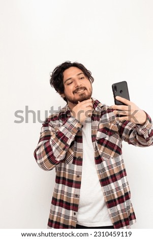 Vertical image of hispanic man making a selfie with his cell phone in white background