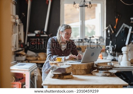 Female carpenter using laptop in a carpentry workshop
