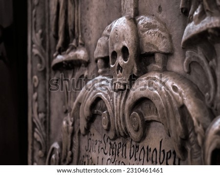Medieval tombstone with carved skull in marble Memento Mori sign Royalty-Free Stock Photo #2310461461