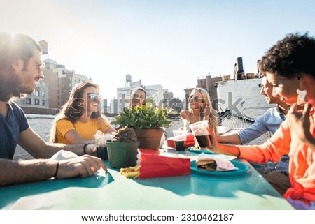 Young happy multiracial people having a barbecue dinner on a rooftop in New York - Group of multiethnicfriends having party and having fun on apartment terrace