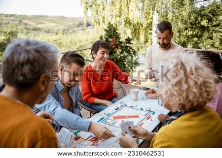 Multiethnic group of diverse people playing board games at home on the patio. Friends enjoying weekend activities and hangout together