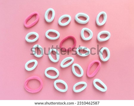 Colored hair ties lie on a pink background