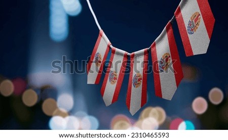 A garland of French Polynesia national flags on an abstract blurred background.