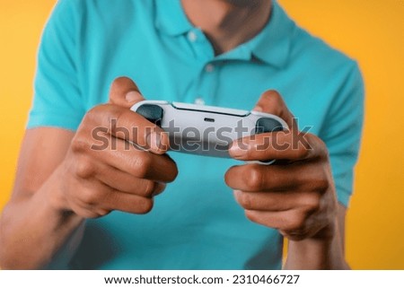 Young man playing video exciting game on Tv with joystick isolated on yellow studio background. Using modern technology.