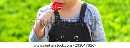 A child eats a lollipop in the park. Selective focus. Kd.