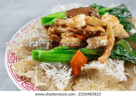 A closeup view of a plate of fried vermicelli with beef, chicken and shrimp.