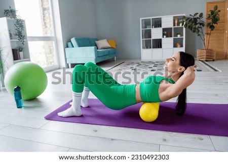 Full body profile photo of determined slender lady doing abs exercise fitness roller carpet living room indoors