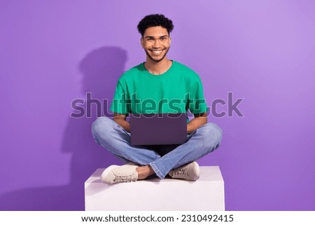 Full body size photo of young guy wear green stylish t-shirt sitting coworking with laptop remote student isolated on purple background