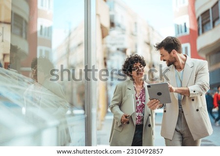 Cropped shot of two coworkers using a digital tablet and talking while standing outside. Modern elegant Coworkers Chatting together In City Street in their way to work Royalty-Free Stock Photo #2310492857