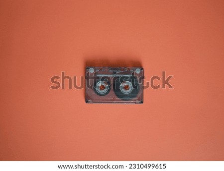 Audio cassette in the middle on an brown background, top view.