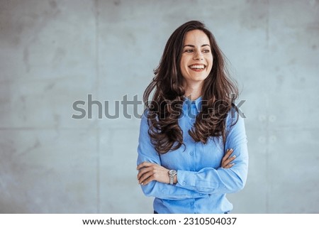 Image of happy young business woman posing isolated over grey wall background. Smiling Pretty Business Woman With Arms Crossed. Portrait of middle aged businesswoman in modern office looking at camera