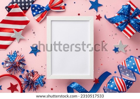 USA Independence Day event. Top view of emblematic decorations, party serpents, shiny stars, confetti, headband, gift parcel, bow-tie on pastel pink backdrop with blank photo frame for ad or picture