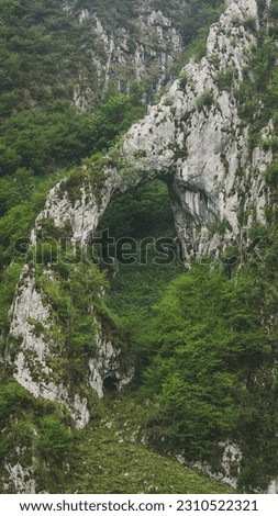 Arch of limestone with green trees all over the hills
