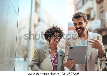Chasing after success with the best connection. Shot of two businesspeople using a digital tablet in the city. Business colleagues are using digital tablet outside the company building. Royalty-Free Stock Photo #2310527205