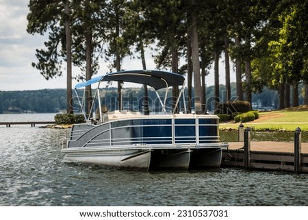 Pontoon boat at private dock on freshwater lake. Royalty-Free Stock Photo #2310537031