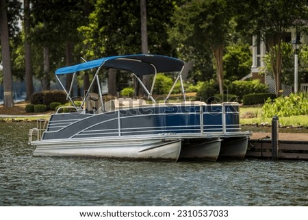 Pontoon boat at private dock on freshwater lake. Royalty-Free Stock Photo #2310537033