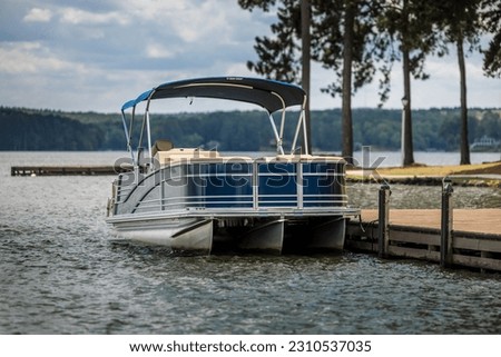 Pontoon boat at private dock on lake. Royalty-Free Stock Photo #2310537035