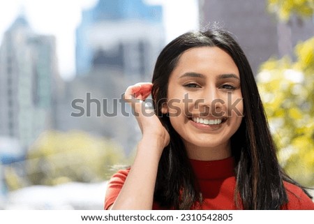 Portrait of beautiful happy Indian woman with toothy smile correct hair looking at camera on the street. Attractive asian model posing for pictures outdoors. Positive lifestyle, natural beauty  