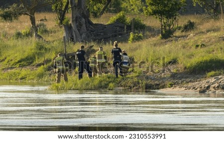 Firefighters and police officers by the river conduct an investigation or activities related to the drowning of a man. Corpse in the river
