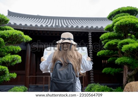 Asian tourist, cute woman with long hair are traveling in Hong Kong along with map and her camera with fun on her holiday, A temple in Hong Kong, concept travel.
