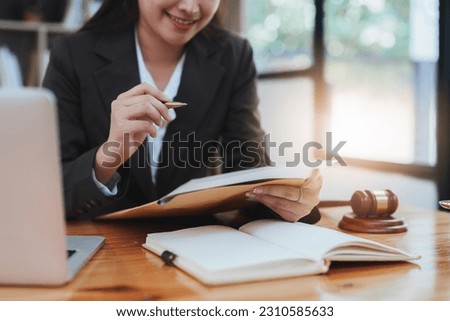 Young lawyer in office Business woman and lawyers discussing contract papers with brass scale on wooden desk in office. Law, legal services, advice, Justice and real estate concept