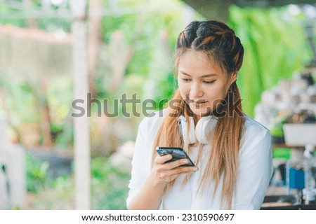 Smiling young asian woman using mobile phone checking social media,app playing game, shopping online, ordering delivery relax  