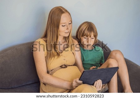 pregnant mom and son look at the tablet. Reading a book or watching a cartoon or making a video call. Look at the photo from the ultrasound