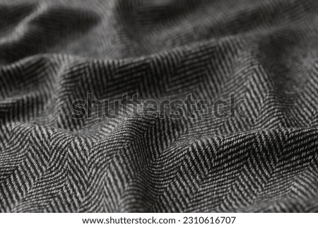 Crumpled black herringbone suit fabric with white stripes for sale in clothing store. Soft textile material texture as background. Catalog photo sample