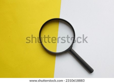 black frame a magnifying glass on rectangle shape colored paper white and bright yellow background