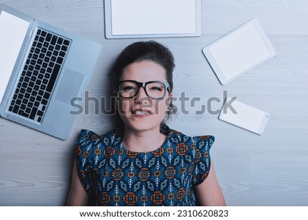 Young woman viewed directly from above thinks, 'all this technology disgusts me, I don't understand anything.' Her head is surrounded by hated machines like computers, smartphones, tablets, and other 