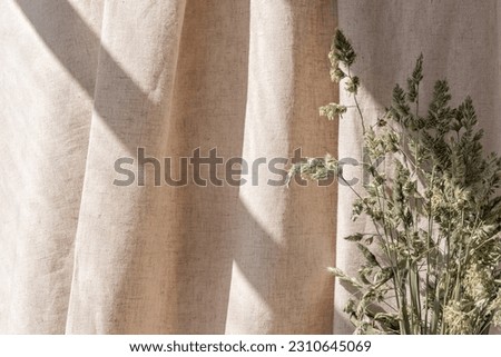 Aesthetic boho neutral floral background, abstract sunlight shadows on a beige linen curtain and meadow grass, elegant business, interior or wedding design template