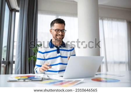 Portrait of male interior designer working at office with color swatches. man at workplace choosing colourful swatches, close-up. Creative people concept.
