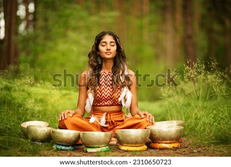 Indian Woman meditating with Tibetan Singing Bowls Outdoors. Yoga Practice in Forest. Spiritual Sound Healing Therapy. Peaceful Nature Relaxation Royalty-Free Stock Photo #2310650723