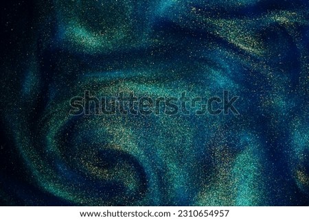 Gold Particles In Blue Fluid. Golden sparkling dust particles floating in a blue liquid with green tints, creating fantasy curved patterns and waves. Magic glittering galaxy.