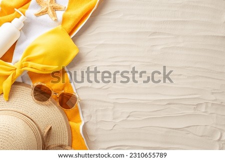 Ultimate summer relaxation. Accessories laid out from top view: sunglasses, sunhat, woman swimsuit, sunscreen, yellow towel, starfish. Sandy beach scene with an empty space for text or promotion