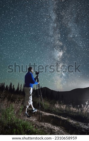Professional photographer taking photos of Milky Way. Young male focusing his camera to take perfect picture of starry sky. Male taking pictures of night sky in mountains.