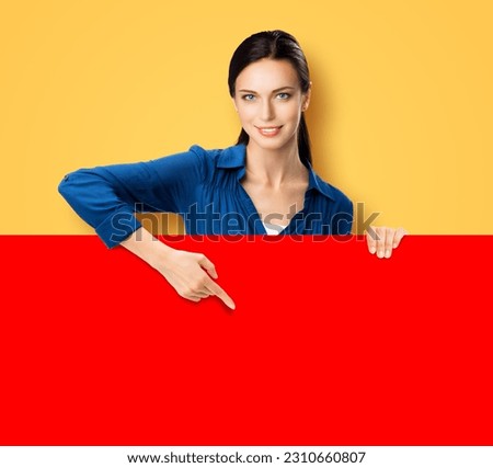 Portrait of beautiful young business woman showing red empty signboard, isolated over yellow background. Sales ad advertisement concept.