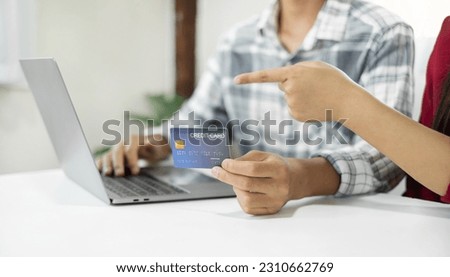 E-commerce Concept. Happy couple holding credit card enjoying doing online shopping and using laptop enter their card number in-app to purchase and payment in internet store.