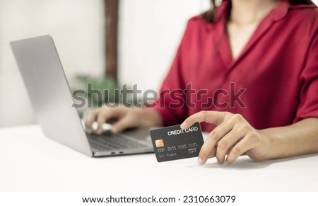The businesswoman hand holding credit card enjoying doing online shopping and using laptop enter their card number in-app to purchase and payment in internet store.