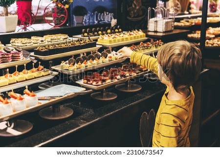 Little boy takes Turkish delights in a five-star hotel, buffet. Royalty-Free Stock Photo #2310673547