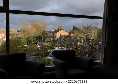 City view from the panoramic window of the hotel with flowering magnolias, blossoming trees and gloomy gray sky