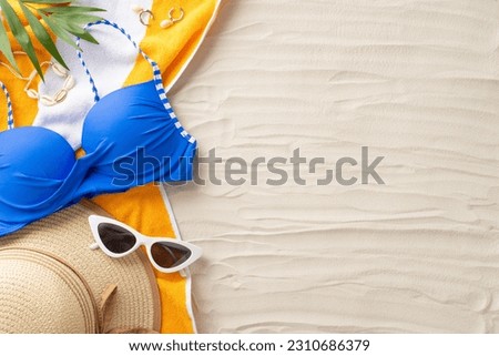 Ready for a bright beach getaway. Top view of summer accessories: sunglasses, sunhat, swimsuit, towel, shell bijouterie, palm leaves. Sandy shore backdrop with an empty space for text or ads Royalty-Free Stock Photo #2310686379