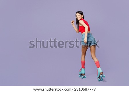 Full body side back view happy young latin woman she wears red casual clothes rollers rollerblading looking camera isolated on plain pastel purple background. Summer sport lifestyle leisure concept