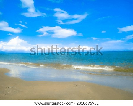 A view of a stretch of beach with a bright blue sky, can be used as a background for photos and others.