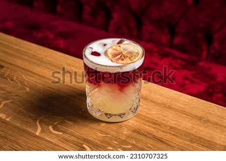 New York sour or Continental sour cocktail with bourbon or whisky garnished with dried lemon wheel at the wooden table at bar or restaurant, horizontal photo